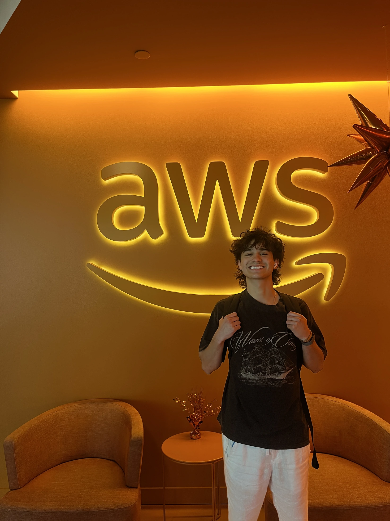 Jose Coy standing in front of an illuminated AWS sign during his internship