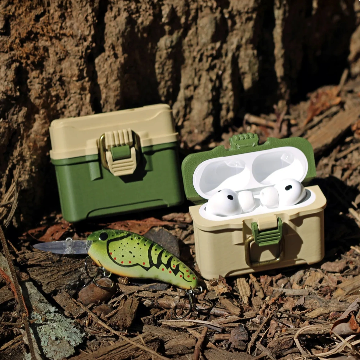 Coy’s finished green-and-tan 3D-printed earbud cases photographed outdoors